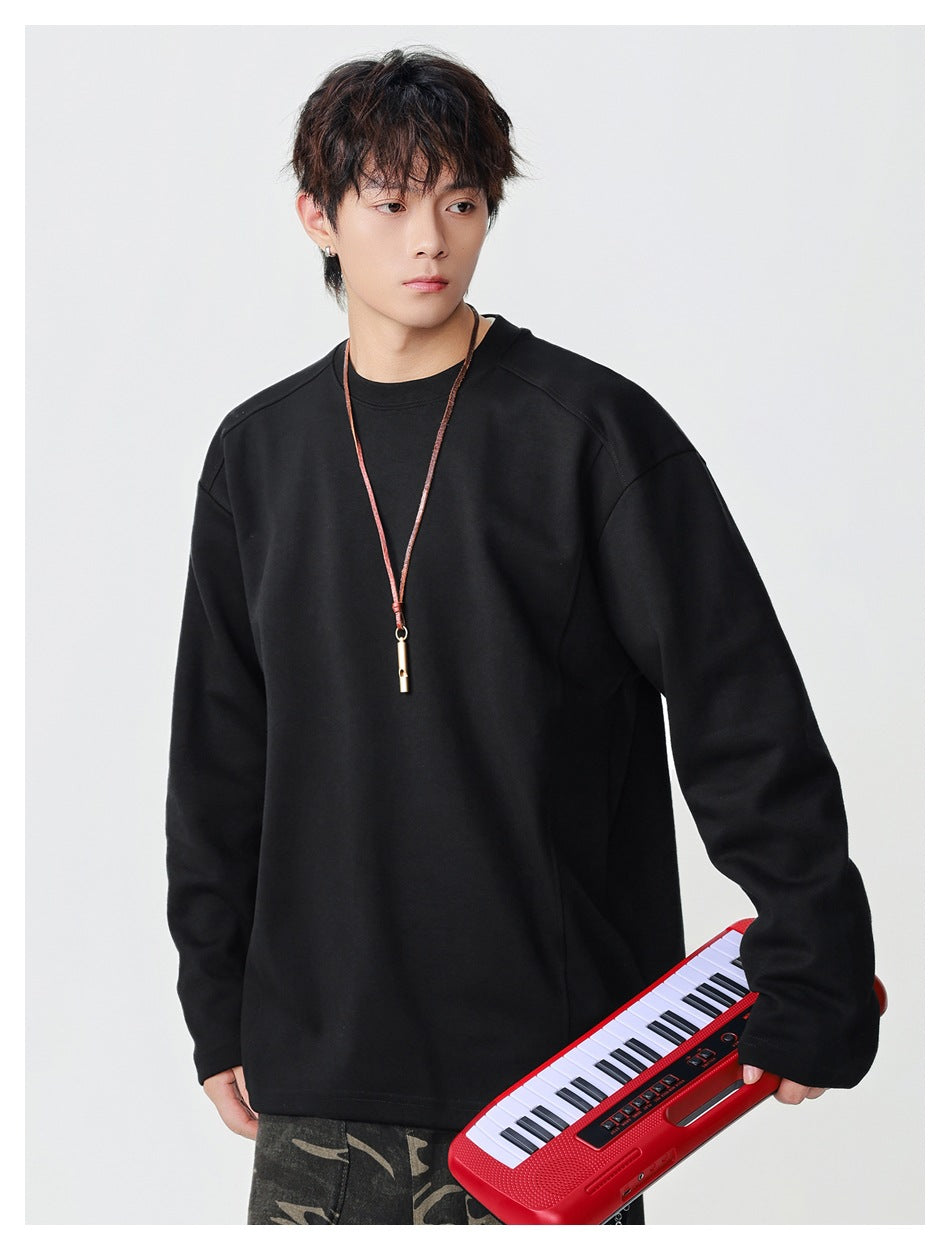 Model wearing an oversized black crewneck top with long sleeves; a red keyboard is held at his side.