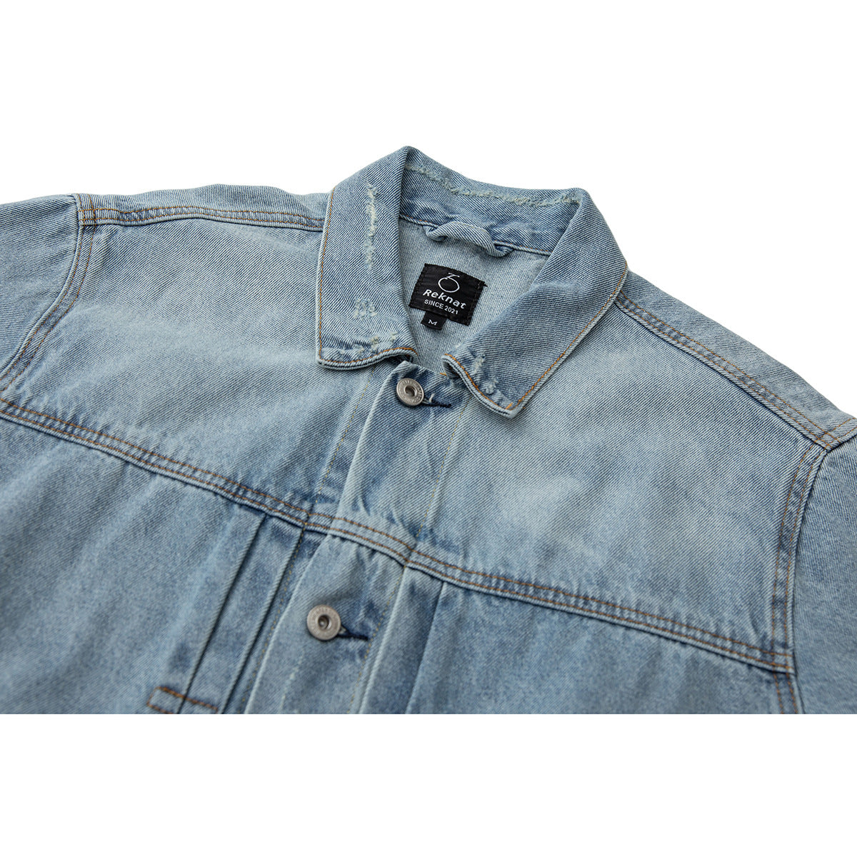 Close-up of a light blue denim jacket collar, metal buttons, orange stitching, and inner neck label.