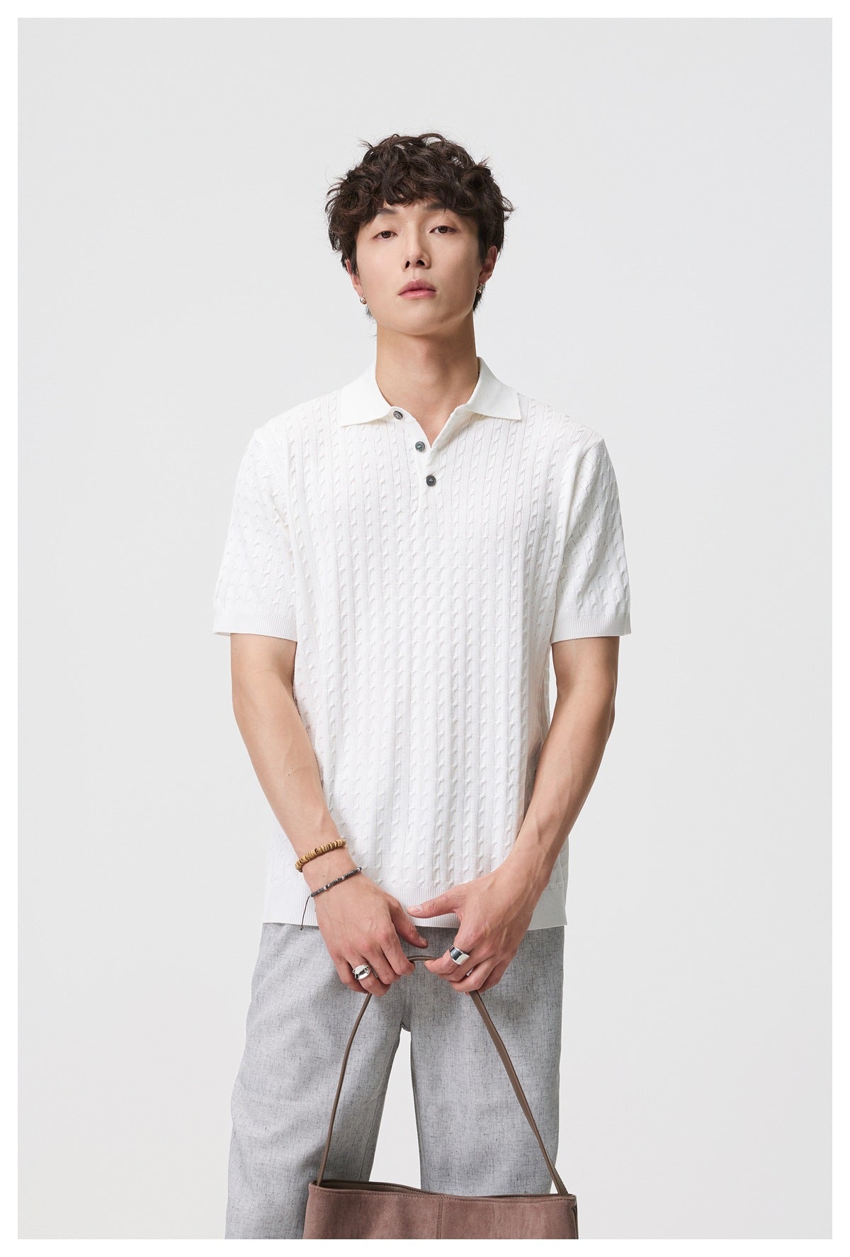 Front view of a model wearing a white short-sleeve cable-knit polo with a collar and three-button placket.
