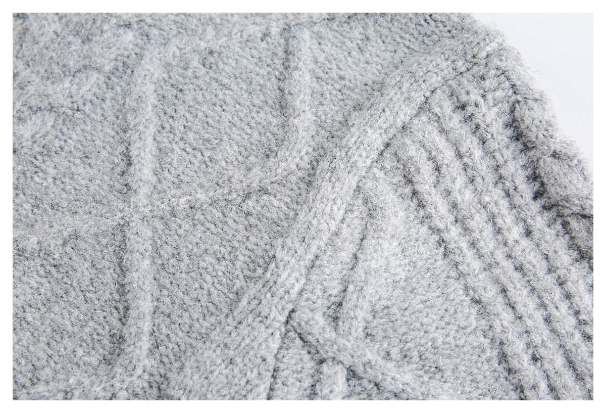 Close-up of a light gray sweater showing textured knit stitches and a raised seam.