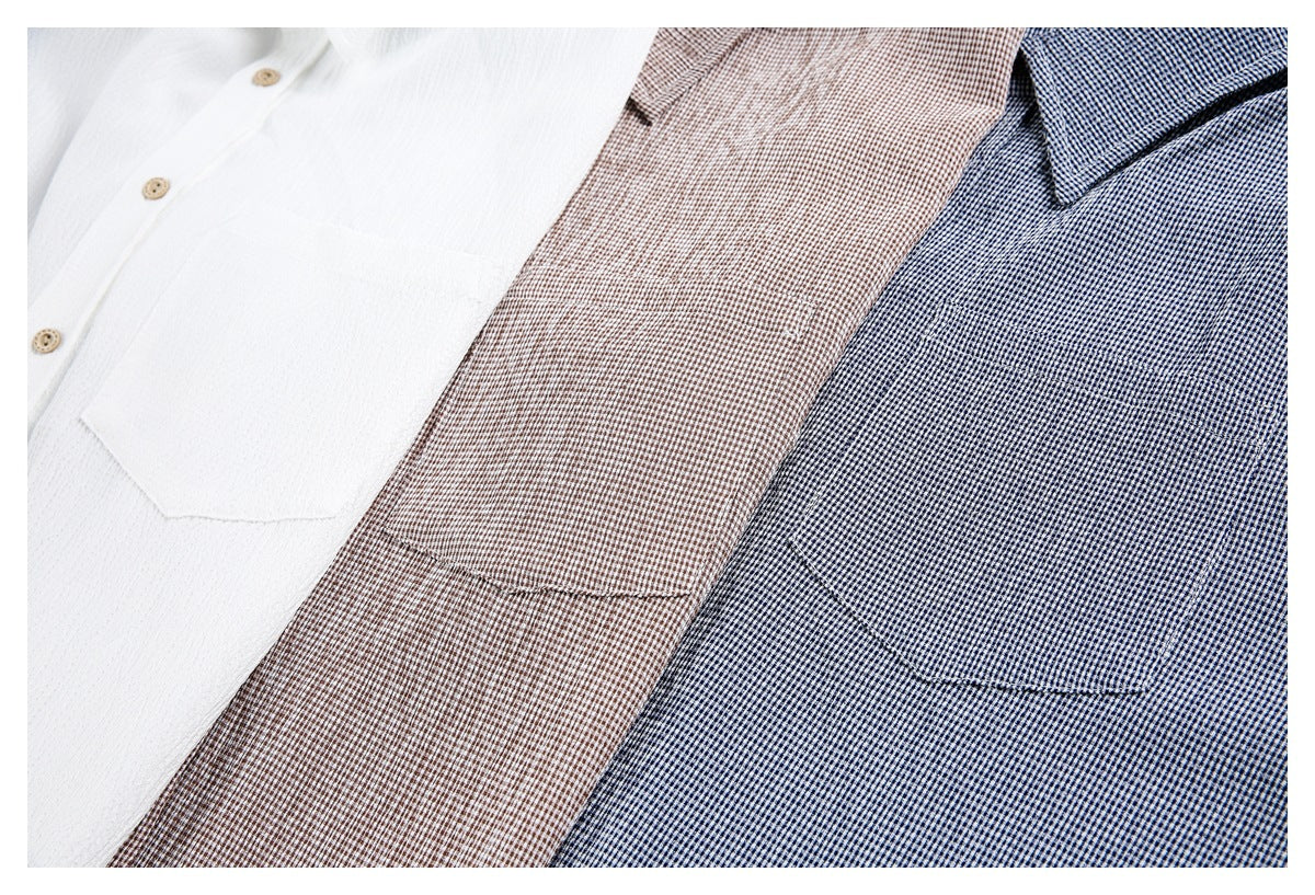 Close overhead view of white, brown-check, and navy-check shirts showing their collars, buttons, and chest pockets.