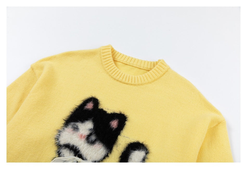 Close-up of the pale yellow sweater's ribbed neckline and partially visible fuzzy black-and-white cat appliqué.