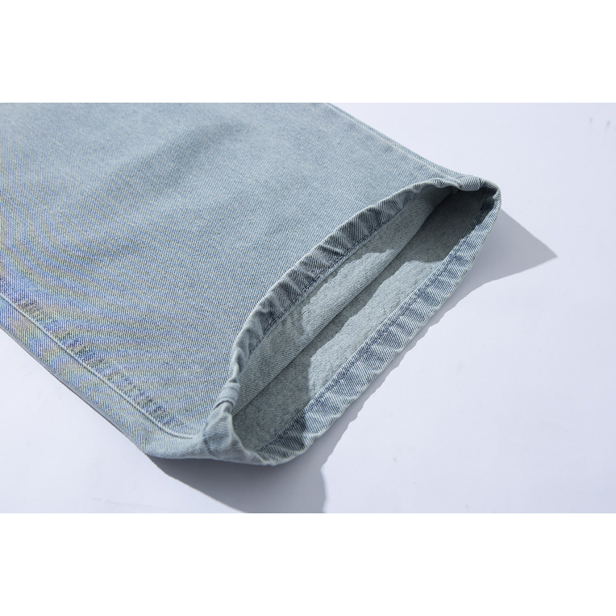 Close-up of the stitched hem and inside of a light-wash jean leg.