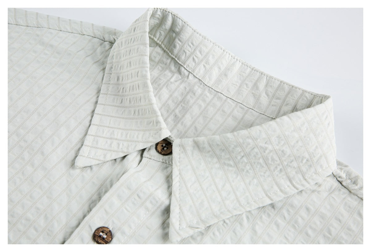 Close-up of a white shirt's pointed collar and brown buttons, showing textured vertical stripes.