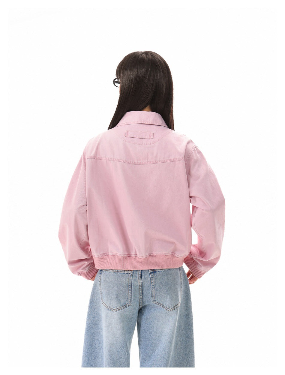 Rear view of a model wearing a light pink collared jacket with ribbed hem and cuffs, paired with light blue jeans.