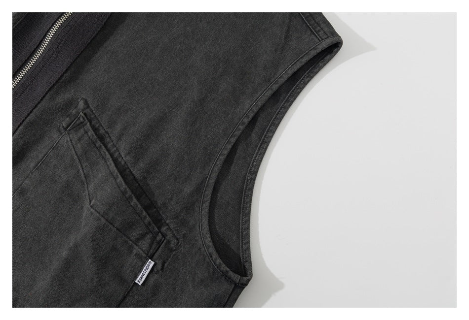 Close-up of a charcoal sleeveless garment showing the armhole, zipper edge, and angled pocket with a small label.