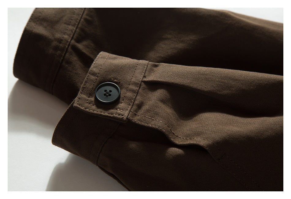 Close-up of a brown garment sleeve cuff with a black button and stitched tab.