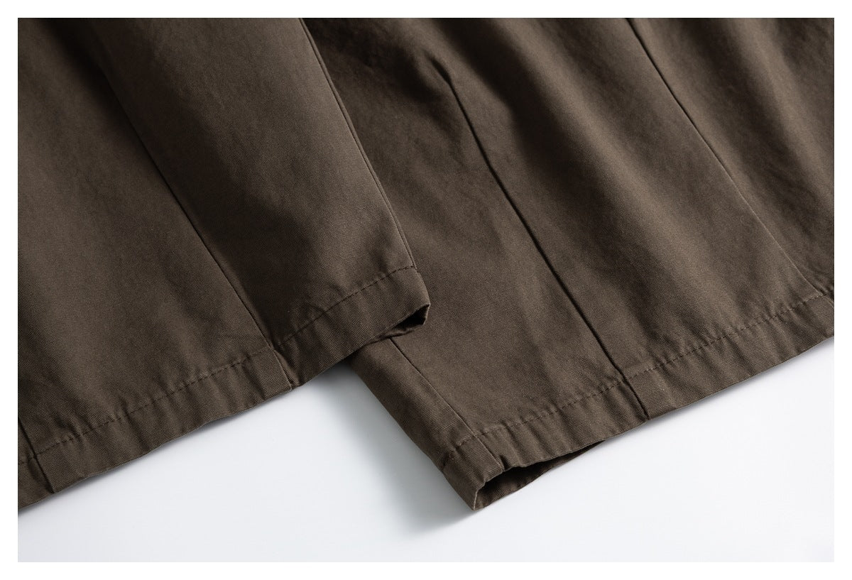 Close-up of dark brown trouser leg hems with double-stitched edges.