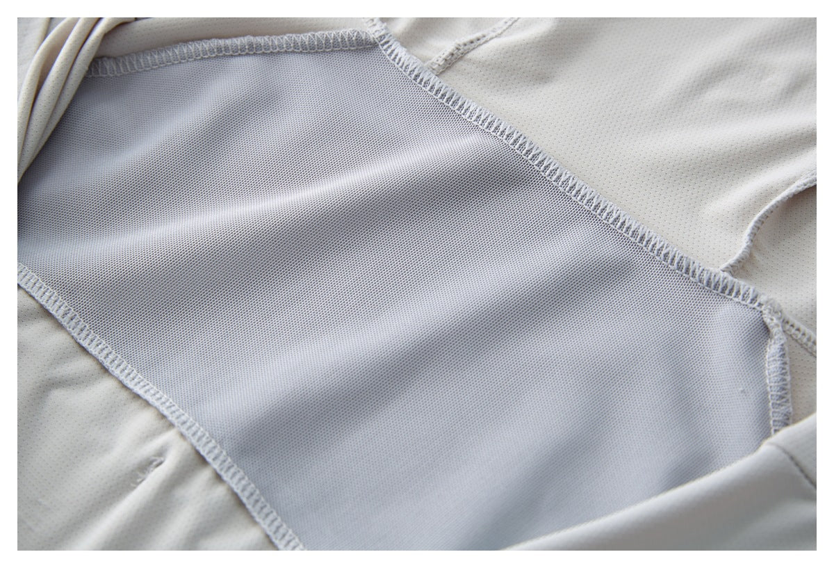 Close-up of the inside of a light gray garment, showing a large mesh panel and stitched seams.