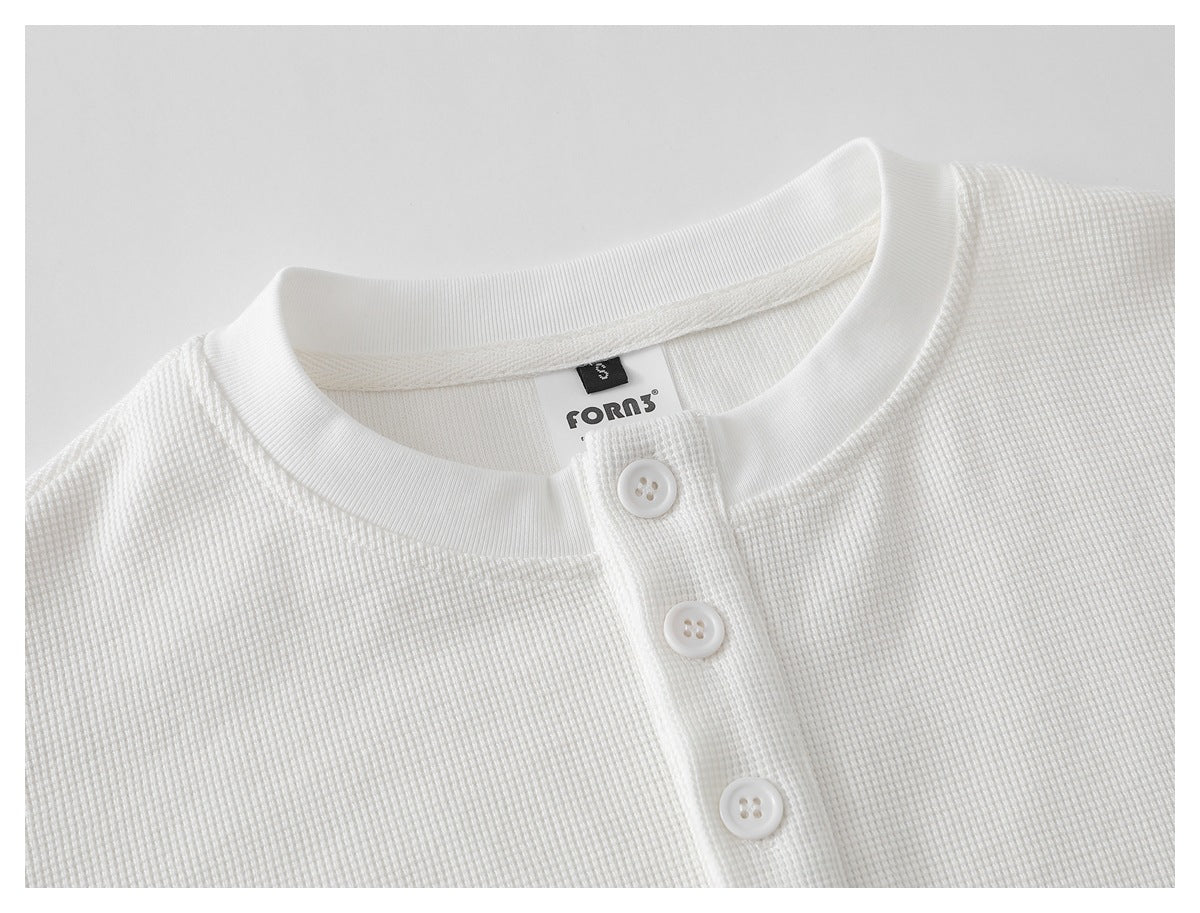 Close-up of a white textured shirt neckline with a ribbed collar and three-button placket.
