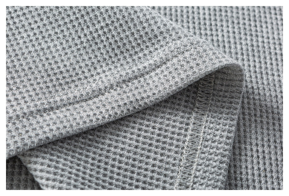 Close-up of gray waffle-knit fabric showing an interior seam and stitching.