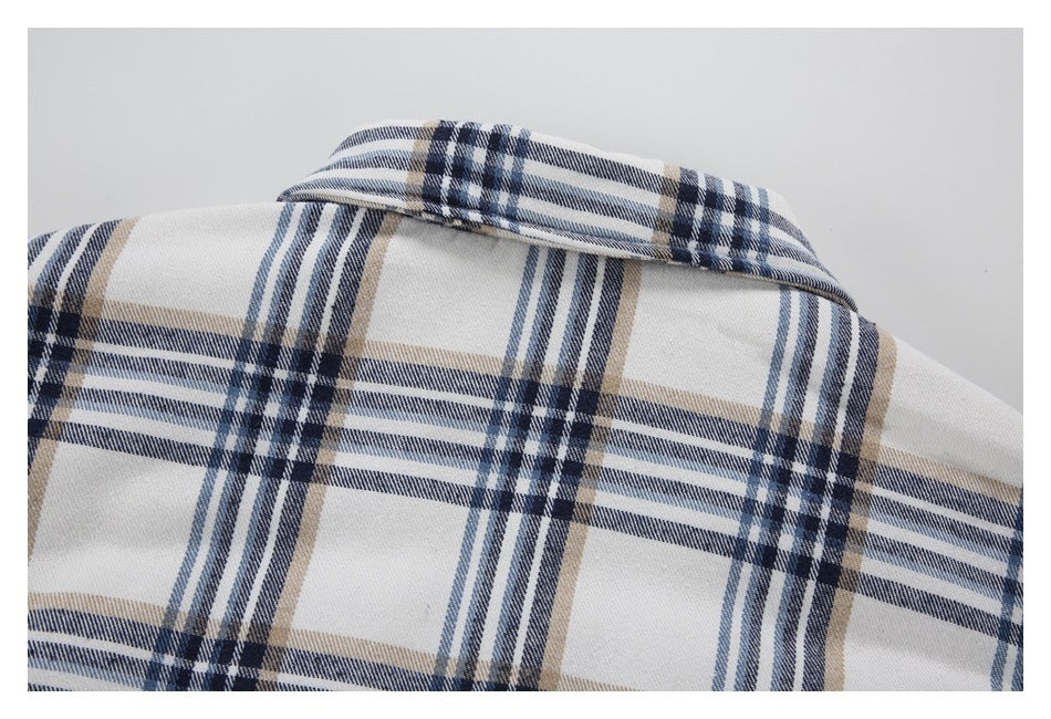 Close-up of a white garment collar with a navy, blue-gray, and tan plaid pattern.