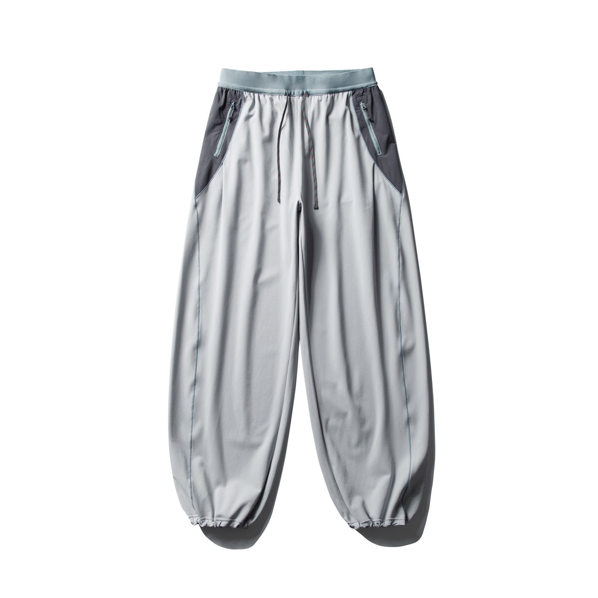 Front view of light gray jogger pants with dark side panels, zip pockets, a drawstring waist, and gathered cuffs.