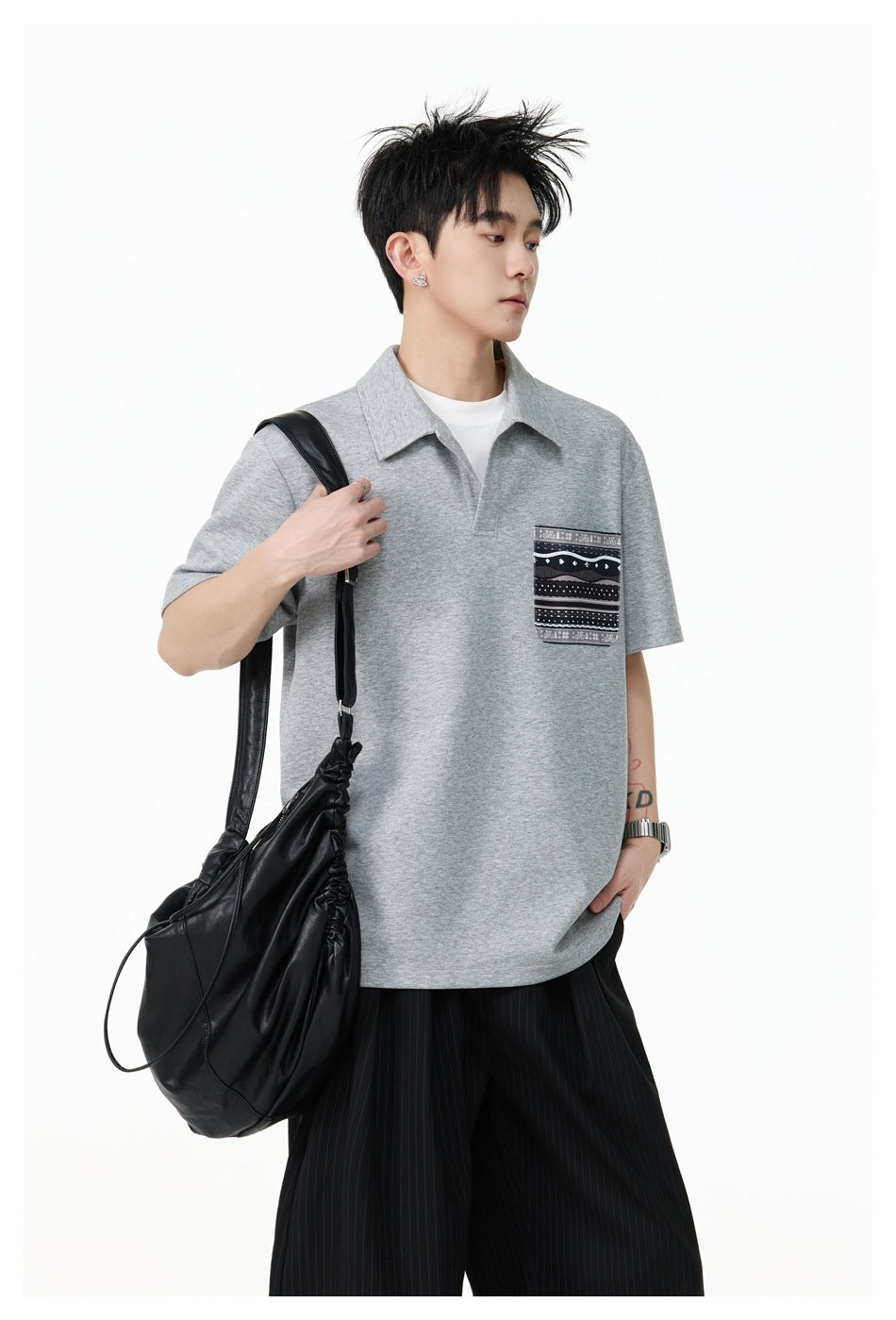 Model wearing a light gray short-sleeve polo with a black-and-white patterned chest pocket.