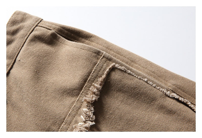 Close-up of tan trousers with a prominent frayed seam and visible woven texture.