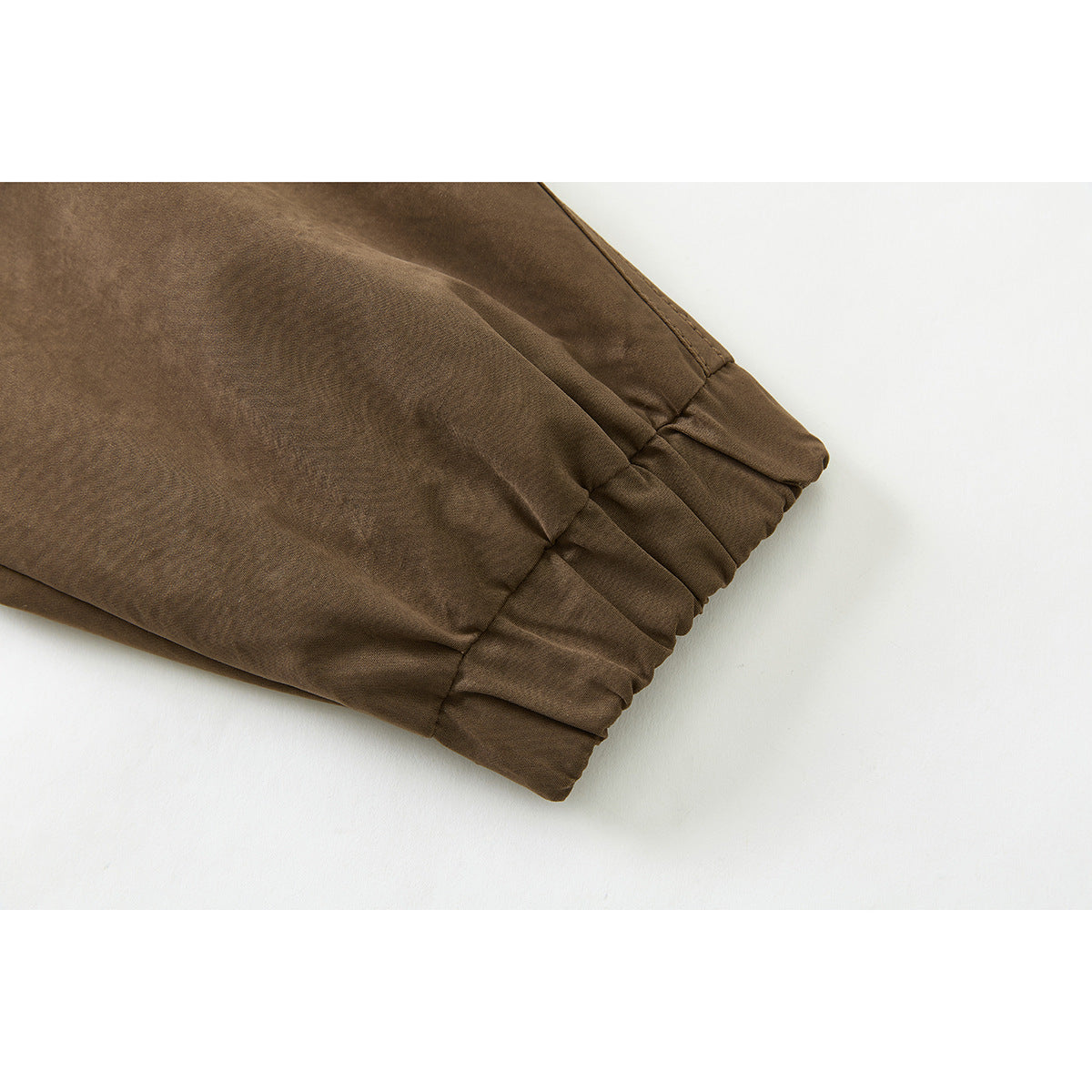 Close-up of the gathered cuff and stitched seam on a brown jacket sleeve.