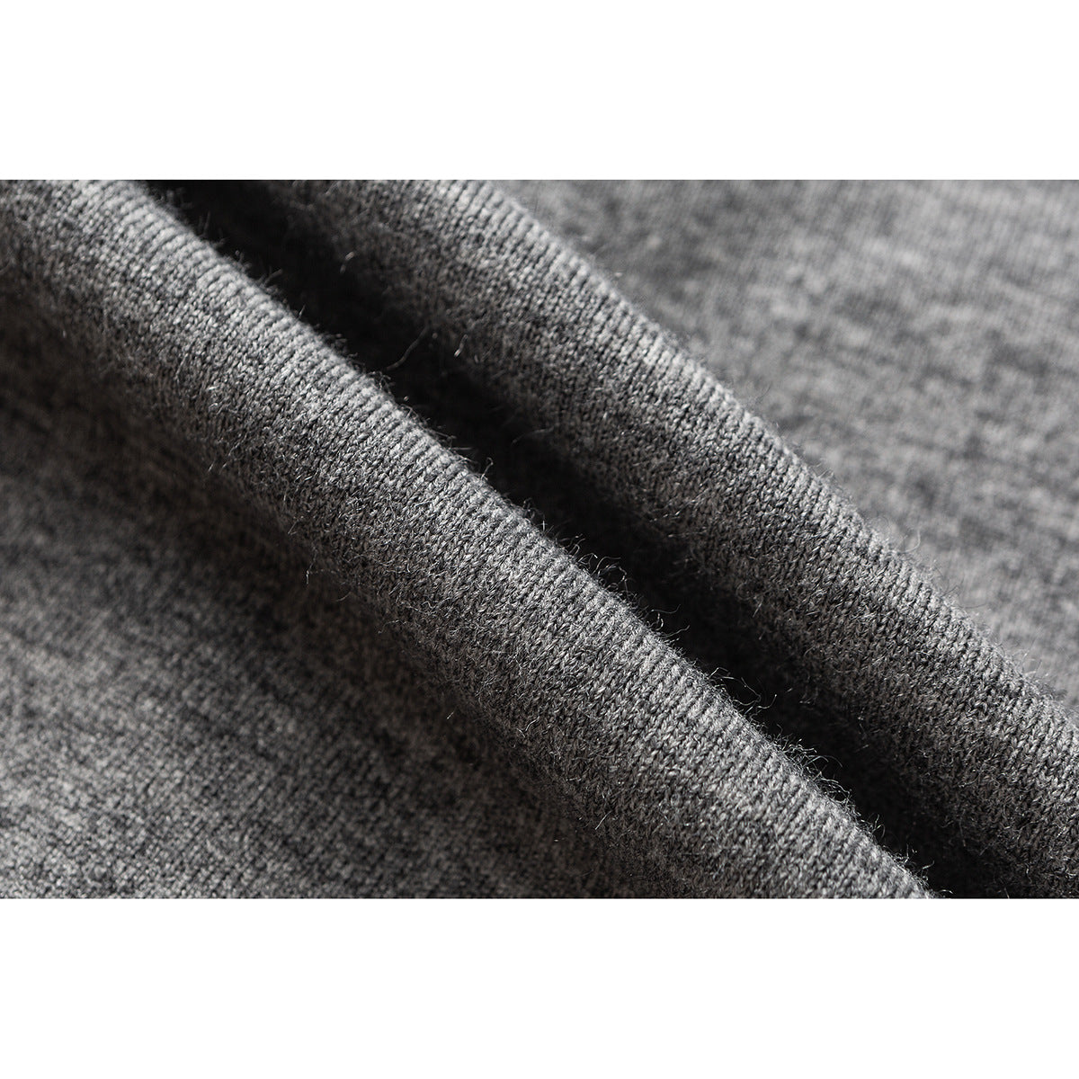Macro view of charcoal gray knit fabric folded to show its texture and edge.