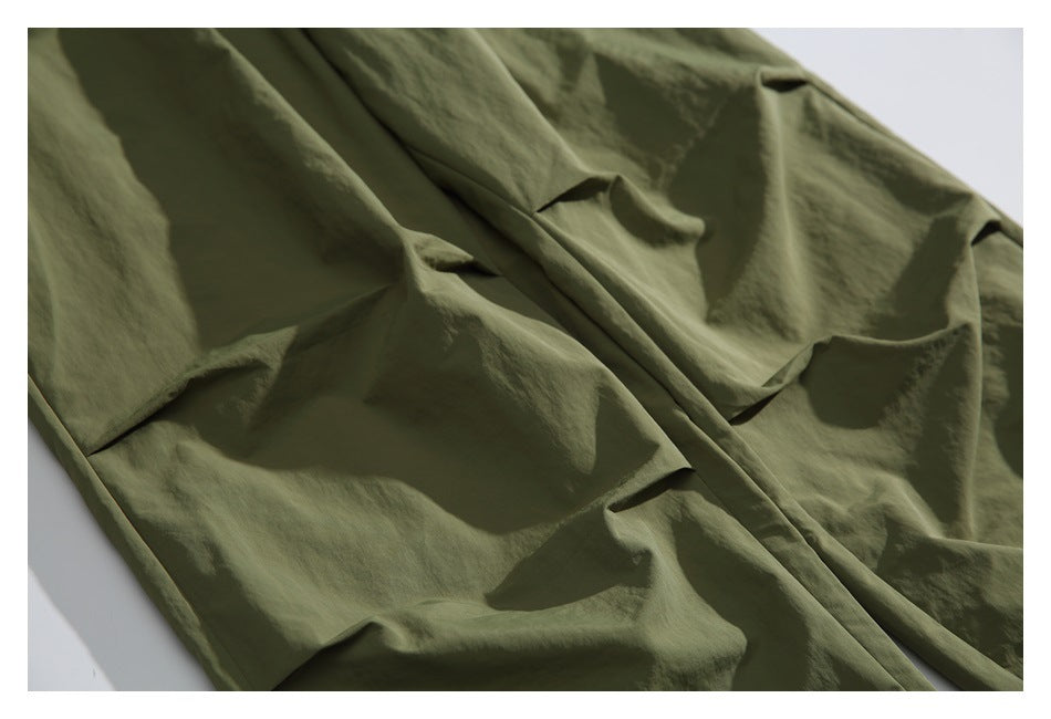 Close-up of the smooth, crinkled olive-green fabric and seams on the pants.