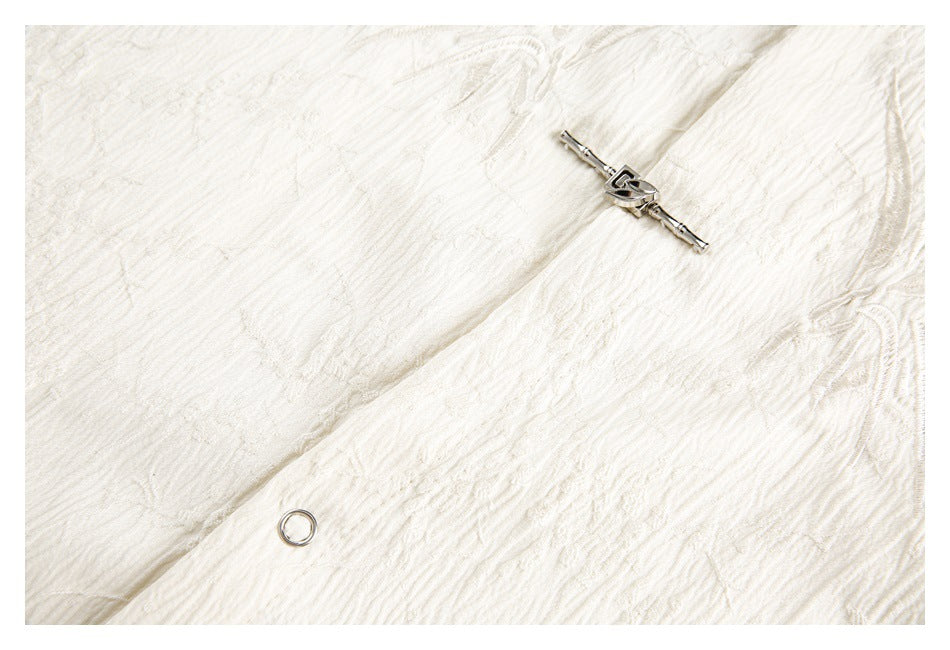 Cream textured fabric close-up with a silver clasp and circular metal eyelet.