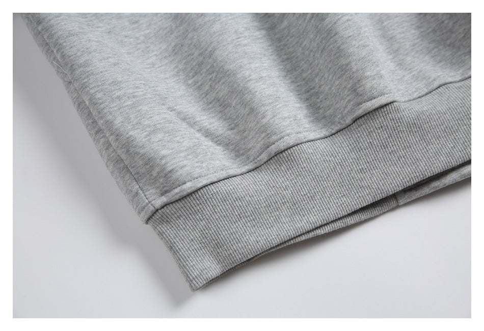 Close-up of a light gray heathered garment with a wide ribbed hem.