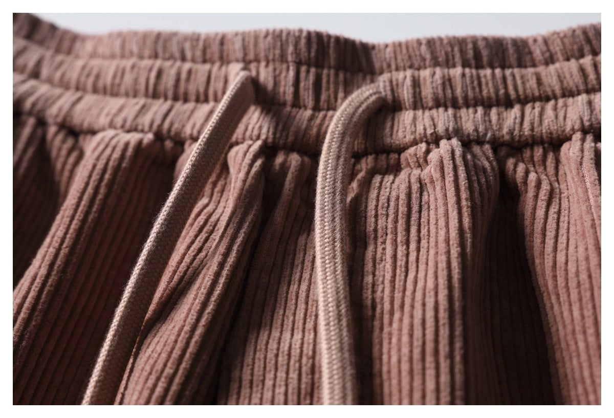 Close-up of dusty rose ribbed trousers with an elastic waistband and two braided drawstrings.
