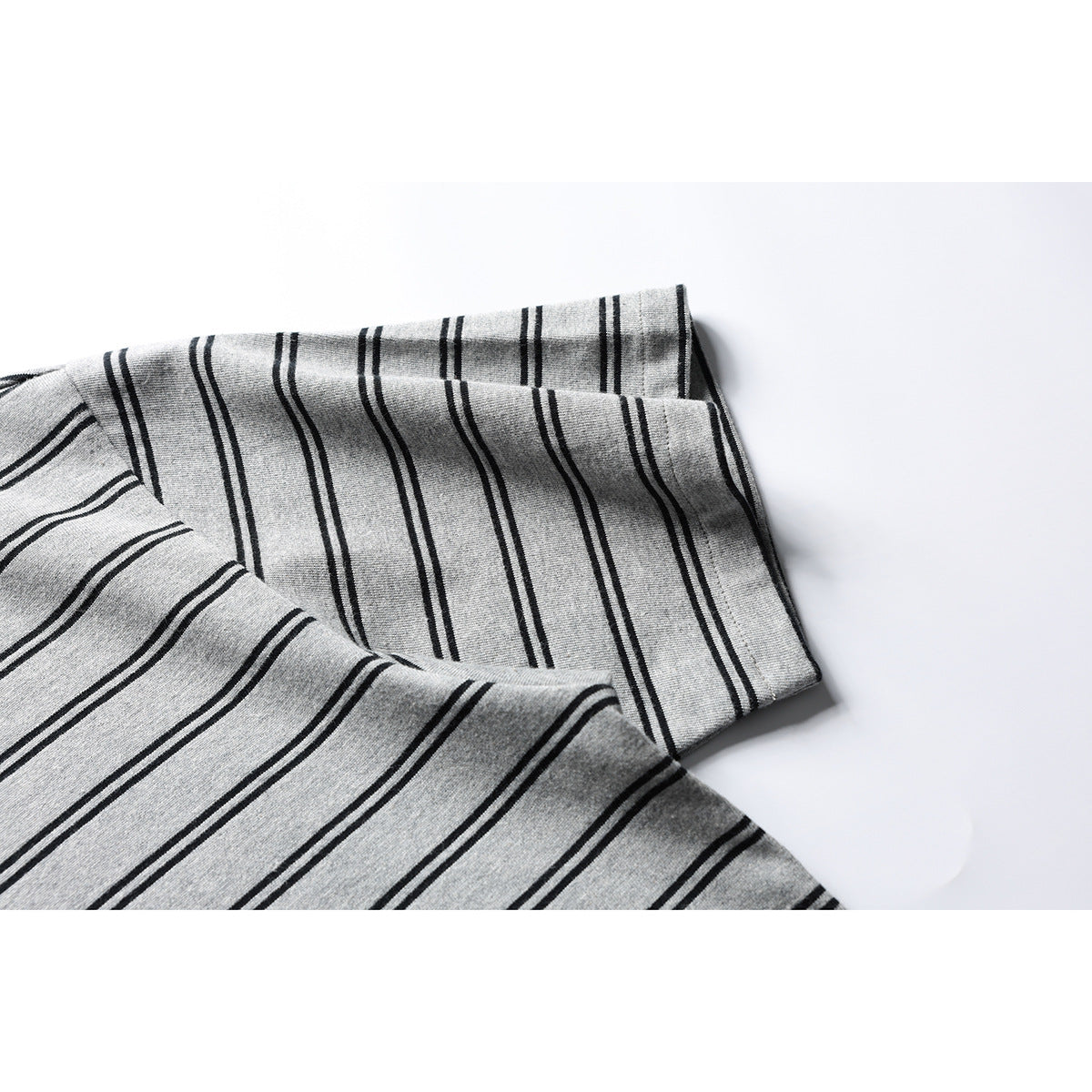 Close-up of the gray shirt's short sleeve and hem, with thin black stripes.