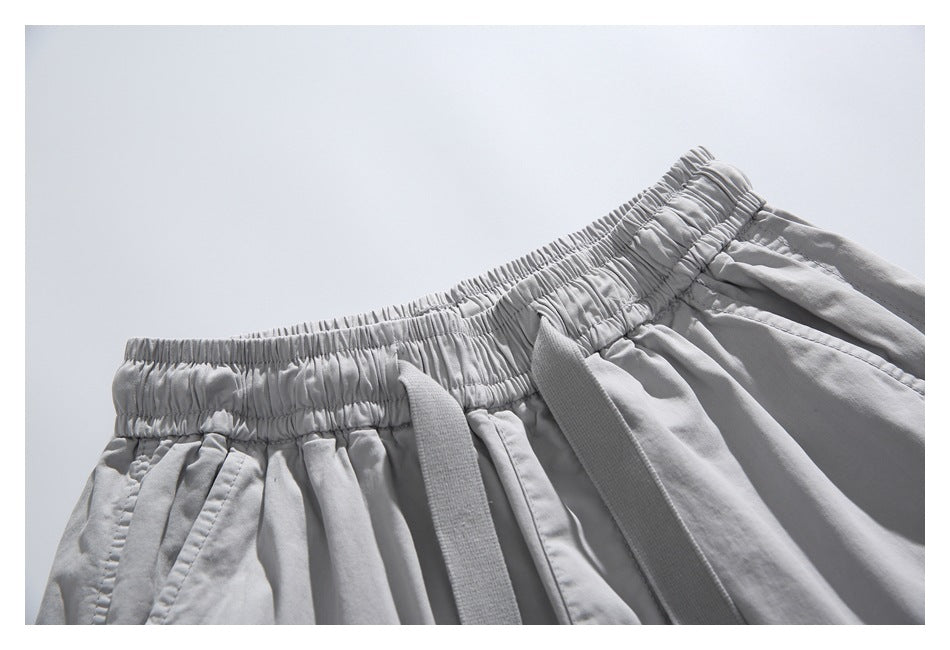 Close-up of the light gray shorts' elastic waistband and two hanging drawstrings.