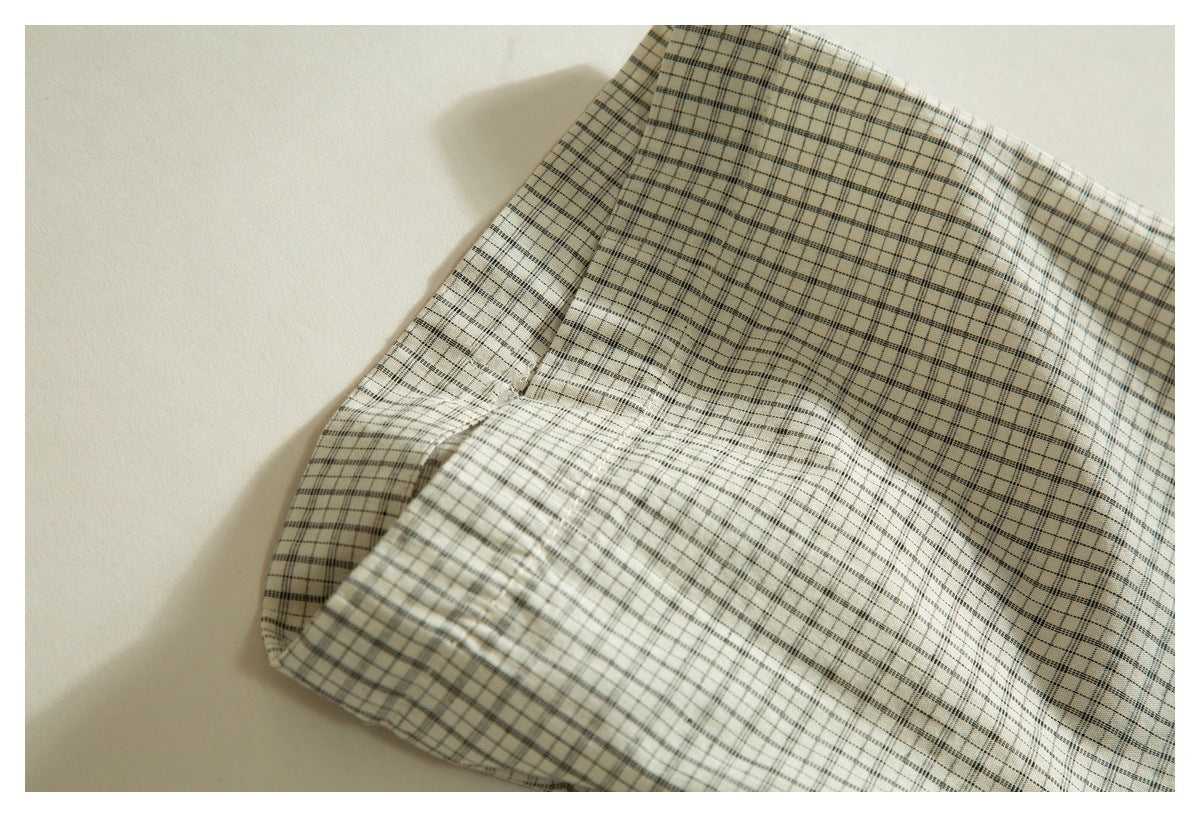 Close-up of the cream plaid shirt sleeve and folded cuff with visible stitching.