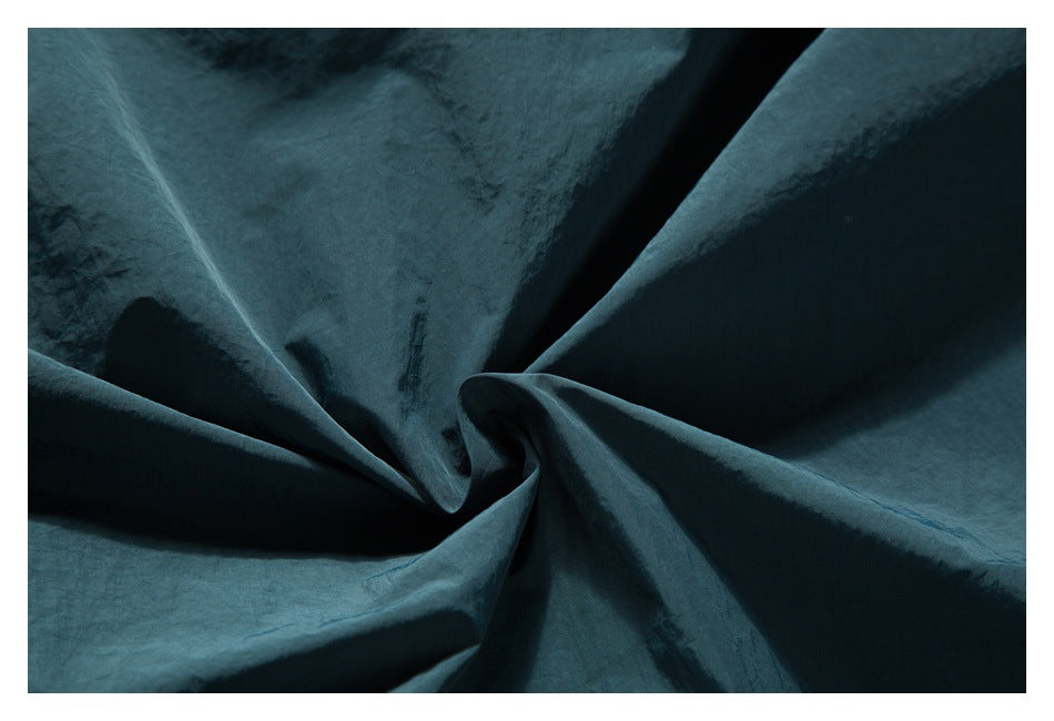 Close-up of dark teal fabric arranged in soft folds.