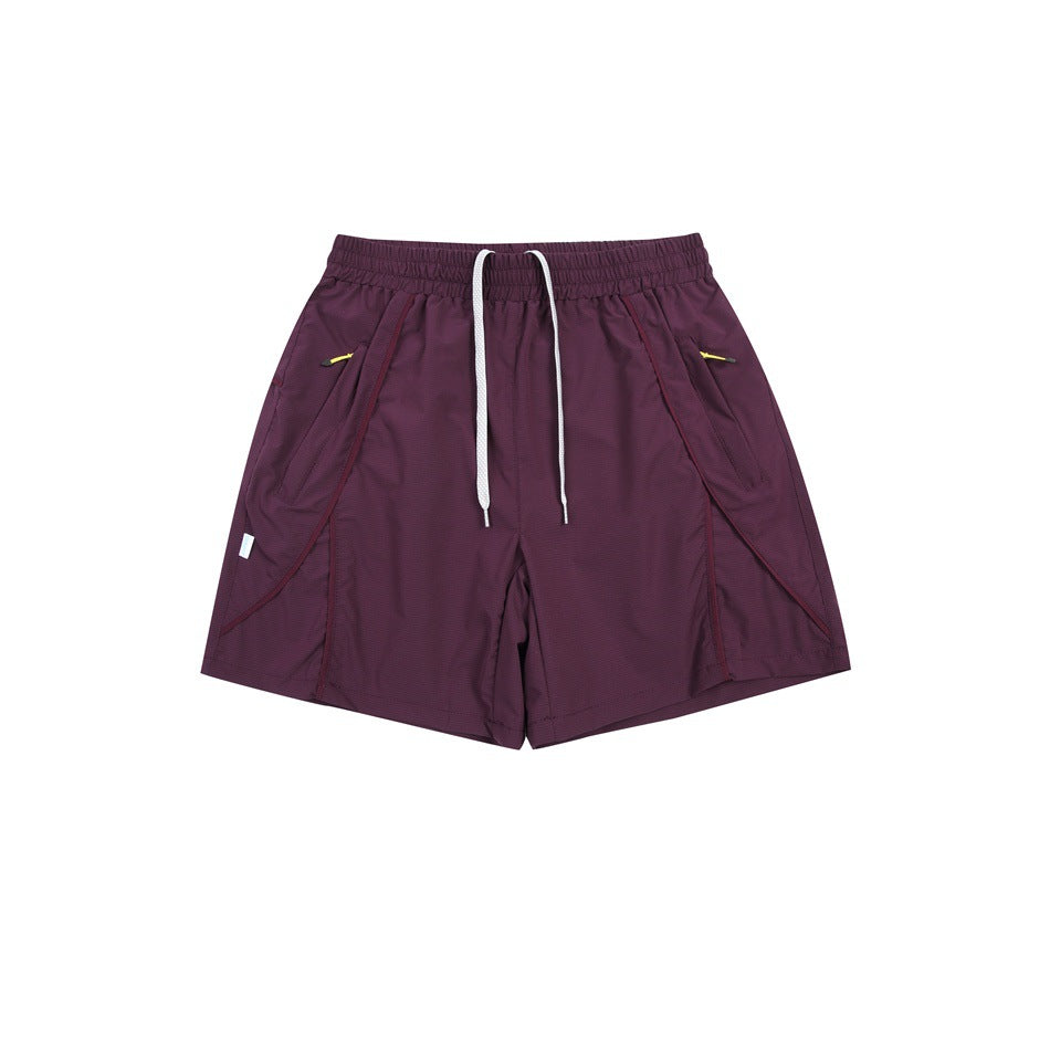 Front view of burgundy athletic shorts with an elastic drawstring waist and angled zip pockets.