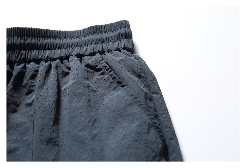 Close-up of the navy shorts' elastic waistband and side pocket opening against perforated fabric.