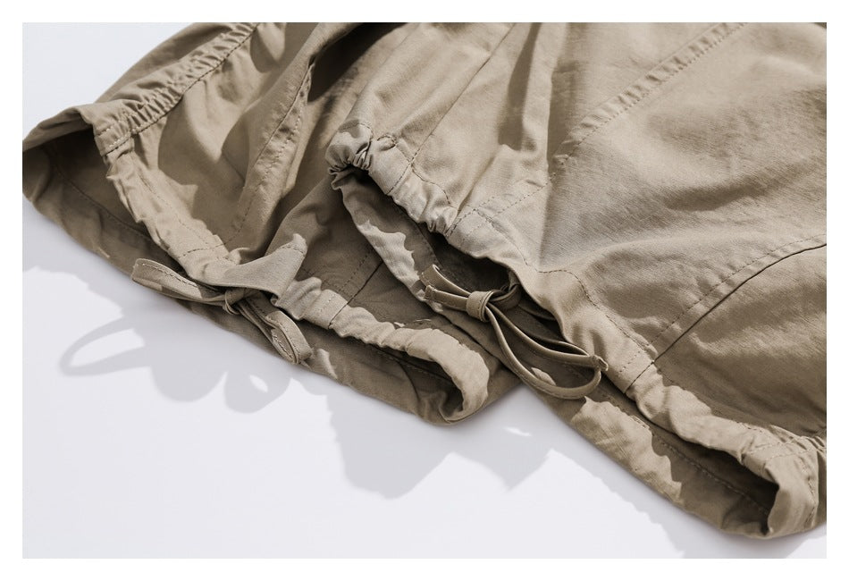 Close-up of beige pants with an elasticized hem and adjustable drawstring ties.