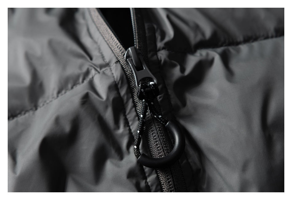 Close-up of a black jacket zipper pull with a cord loop against dark gray quilted fabric.
