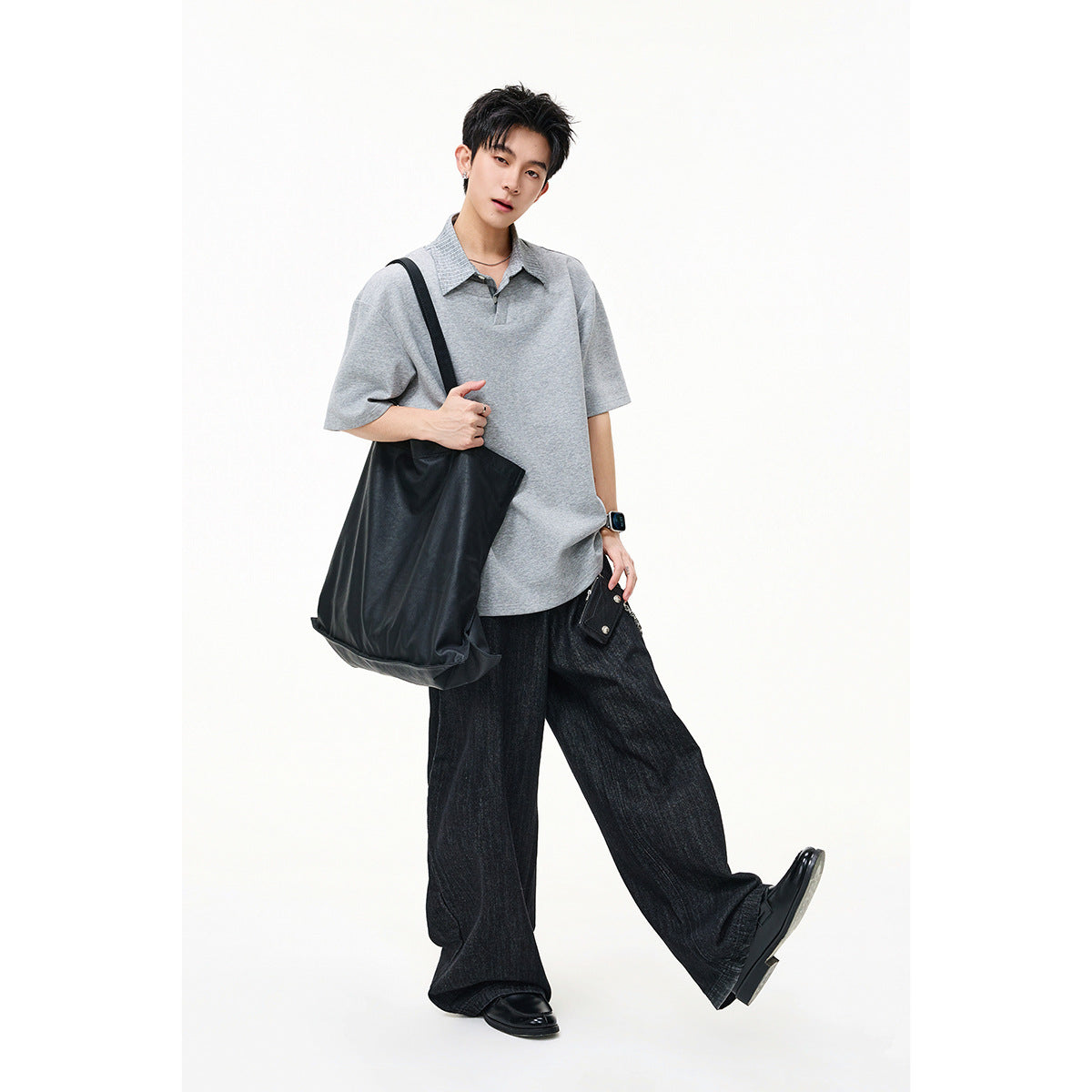 Model standing in a light gray short-sleeve top with a striped collar and wide black trousers.