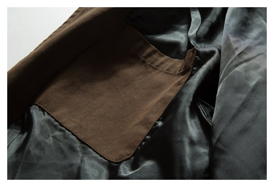 Interior close-up of a brown garment with a rectangular pocket against dark lining.