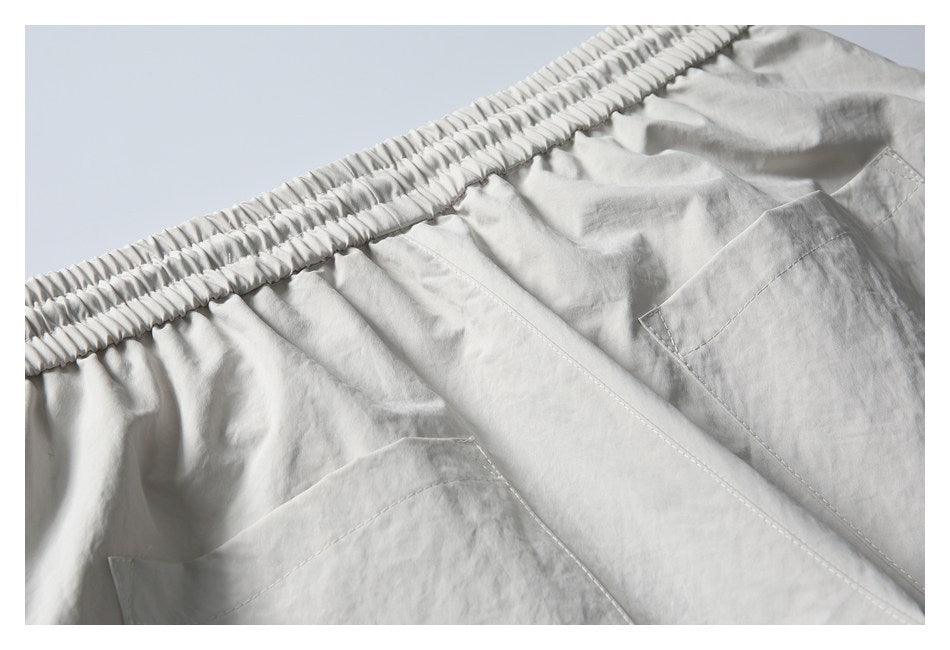 Close-up of light gray shorts with a wide elastic waistband and angled pockets.