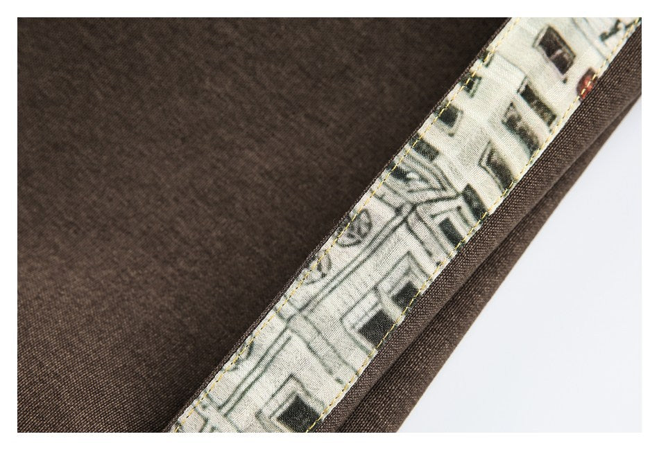Close-up of dark brown fabric with a narrow cream printed trim featuring a building illustration.