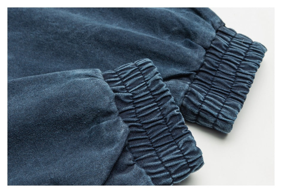 Close-up of gathered elastic cuffs on dark blue denim sleeves.