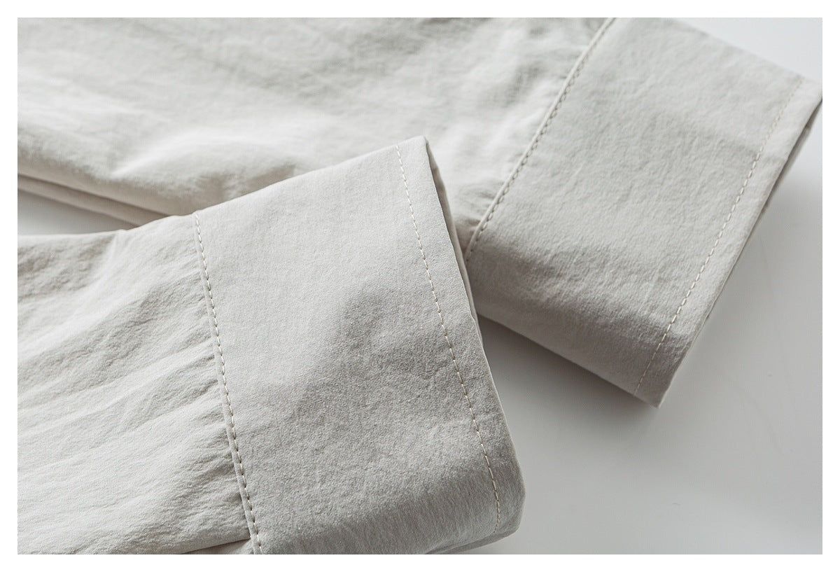 Close-up of a wide cuff and stitched sleeve on light gray-beige fabric.