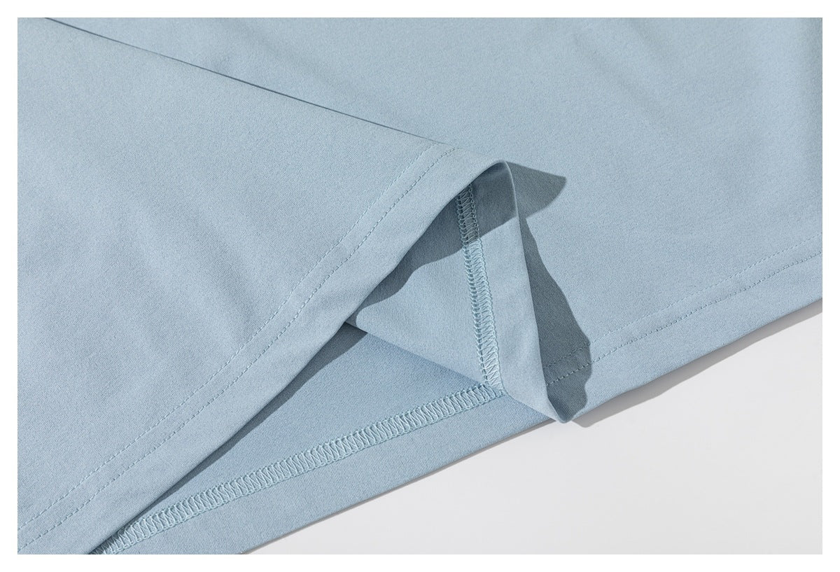 Close-up of the bottom hem and overlocked inner seam on a light blue T-shirt.