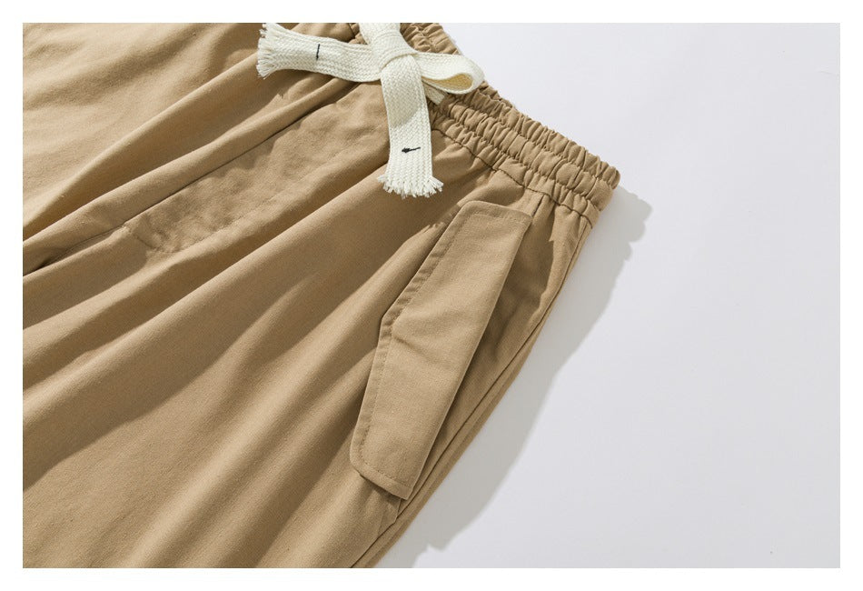 Close-up of tan pants showing a white drawstring and an angled flap pocket.