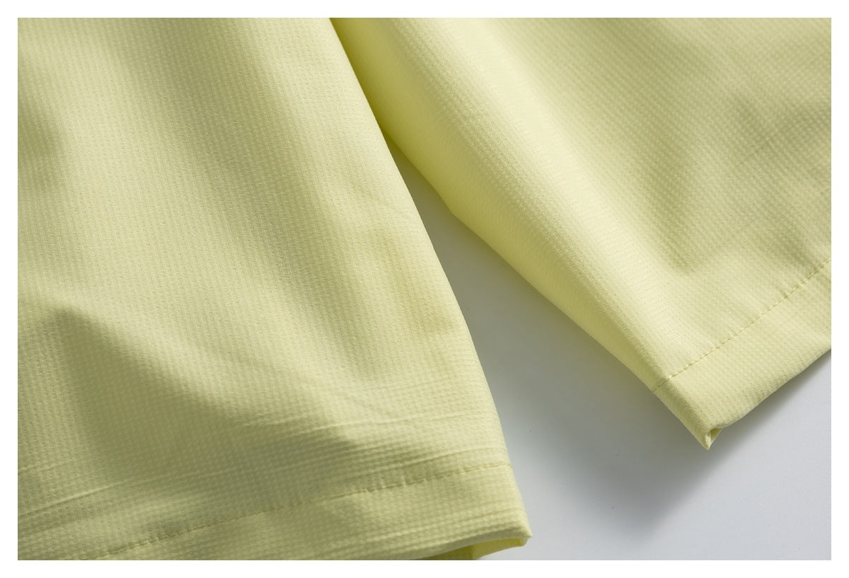 Close-up of the stitched hem on pale yellow garment legs.