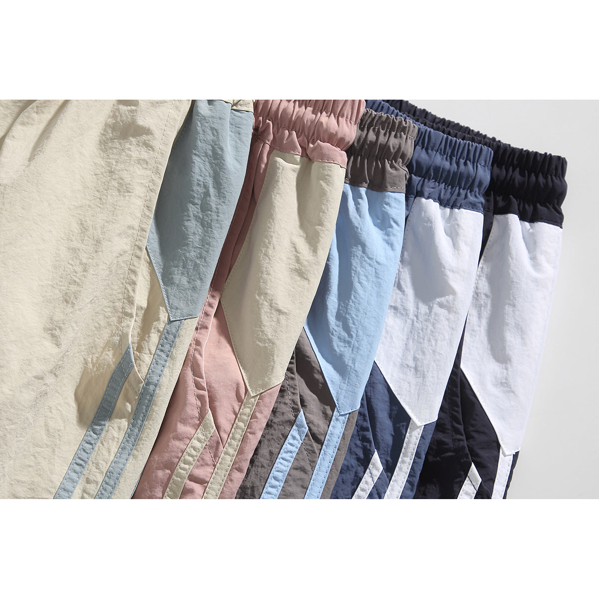 Close-up of color-block athletic shorts arranged in cream, blue, pink, gray, navy and black colorways.