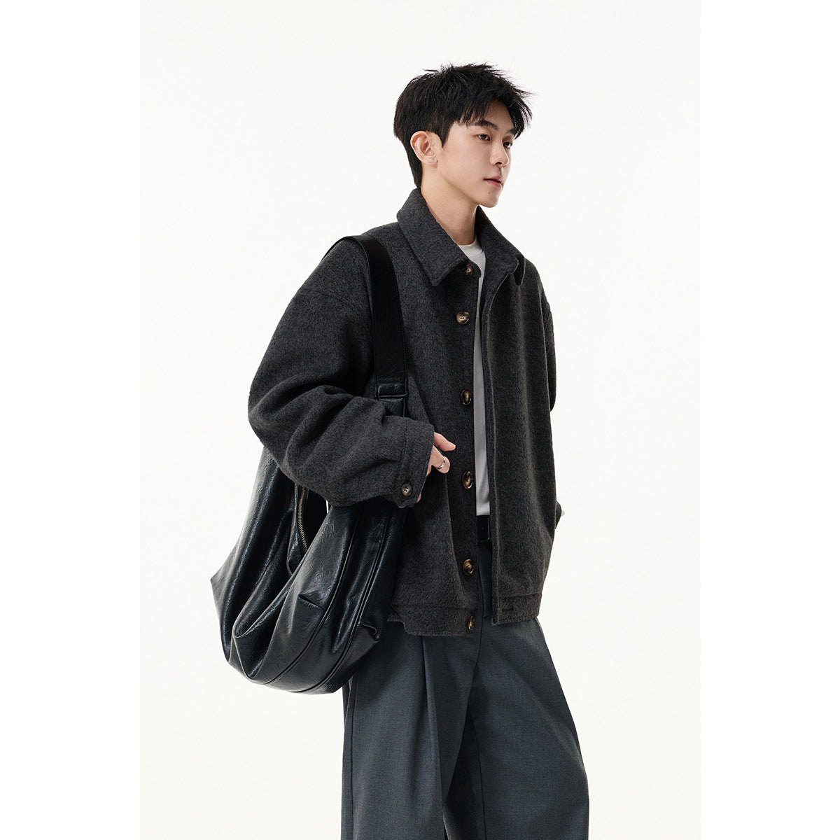 Person wearing a charcoal button-front collared jacket, shown at a slight angle with a black shoulder bag.