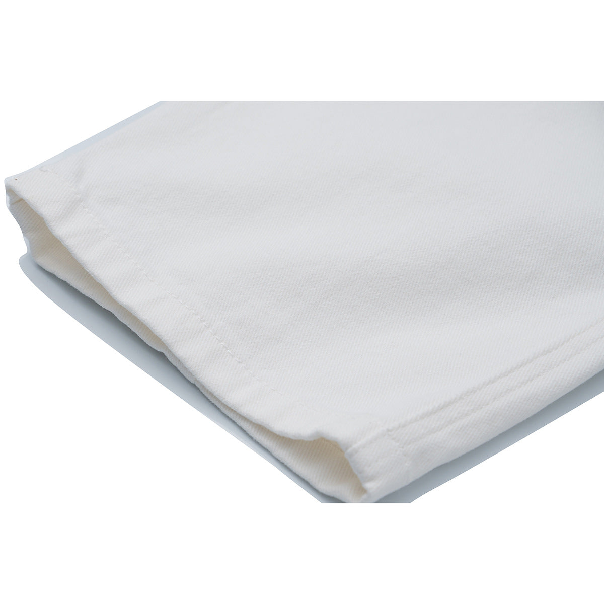 Close-up of the hem and stitching on white trousers.
