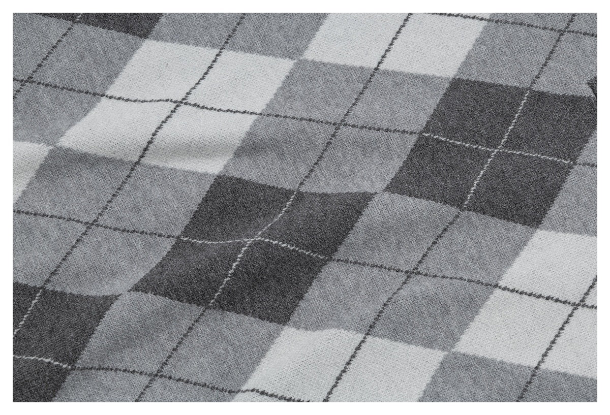 Close-up of a gray and charcoal argyle knit pattern with thin intersecting lines.