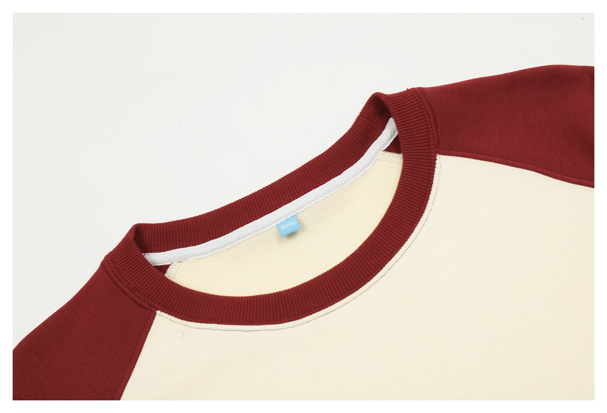 Close-up of the burgundy ribbed collar and cream body of a raglan sweatshirt.