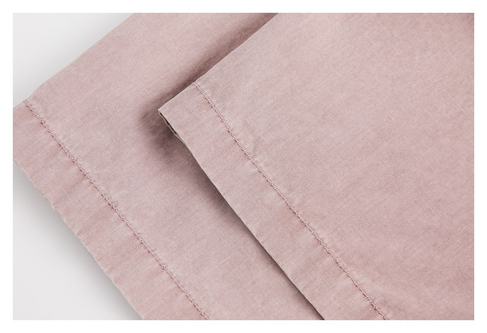 Close-up of dusty pink garment fabric folded to show a stitched edge and seam.