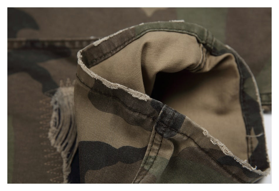 Close-up of a turned fabric edge and seam on camouflage pants, with fraying visible nearby.