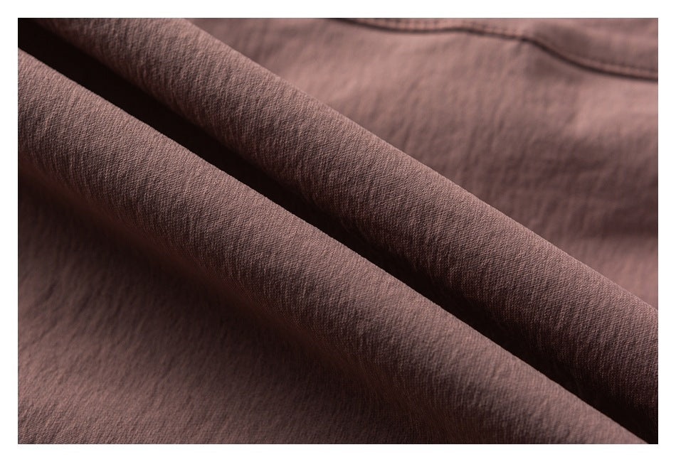 Macro view of the dusty mauve jacket's textured fabric draped into a soft fold.